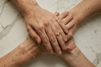 Deux mains entrelacées portant des alliances discrètes en or sur fond de marbre blanc, symbole d'un pacs élégant